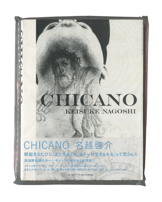 Photobook front cover with obi, Keisuke Nagoshi, CHICANO, Tokyo Kirara-sha / Kawade Shobo Shinsha, Japan, 2008. Sealed in original distributor shrinkwrap. Full-bleed black-and-white photograph — close-up of heavily tattooed torso and neck, head tilted back; dense religious and figurative tattoo imagery including a face, hands, and decorative motifs covering the skin. Bold black serif title 'CHICANO' and 'KEISUKE NAGOSHI' centred over image. Lower third: wraparound obi in white with cyan Japanese text — 