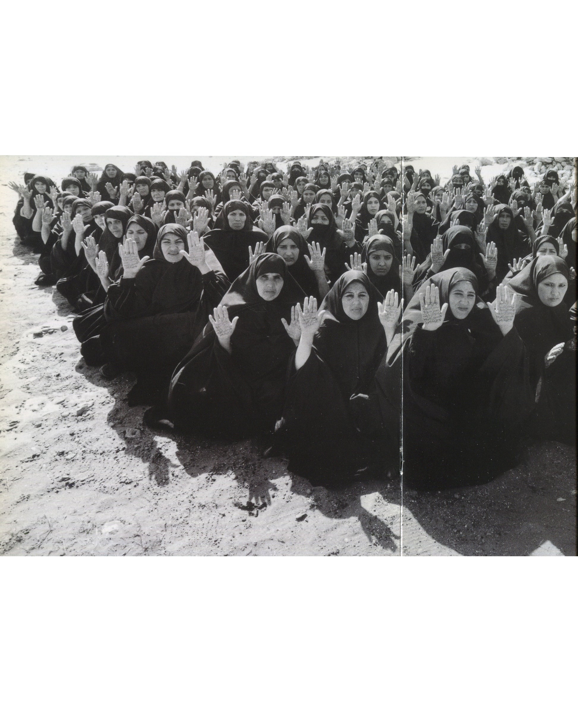 Shirin Neshat, Rapture, 1999, crowd of women in black chadors seated on ground, hands raised toward camera 