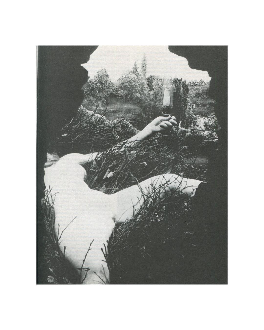 `New Observations No. 84, Alchemy — interior spread. Black and white photograph of Marcel Duchamp's Étant donnés, 1946–66: a reclining female figure amid twigs and branches, one arm raised holding a gas lamp, viewed through a torn aperture in a dark ground.