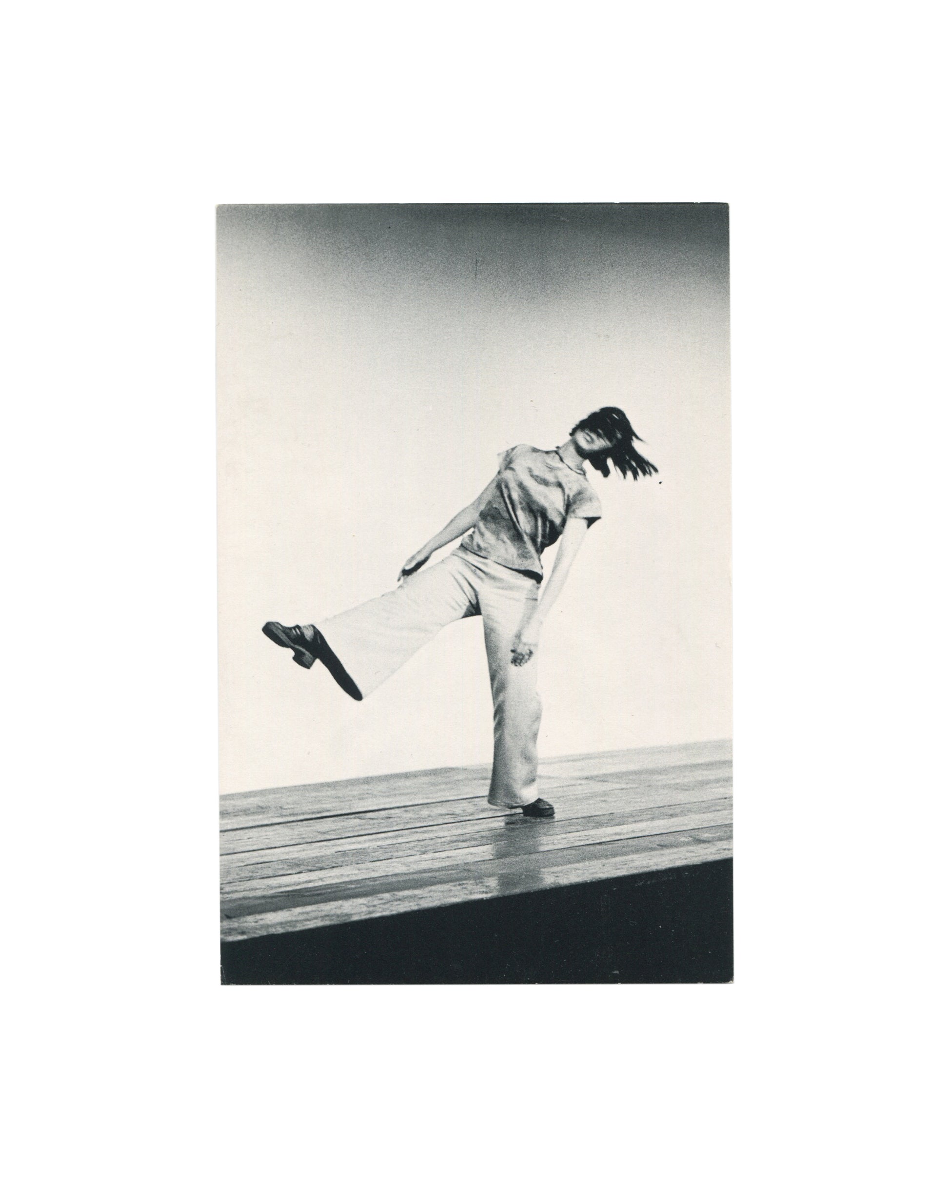Original 1973 Yvonne Rainer and John Erdman performance postcard showing a black-and-white photograph of Yvonne Rainer performing *Trio A*, balancing with one leg raised on a stage.