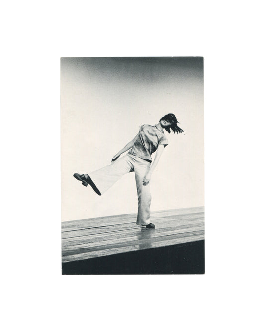 Original 1973 Yvonne Rainer and John Erdman performance postcard showing a black-and-white photograph of Yvonne Rainer performing *Trio A*, balancing with one leg raised on a stage.