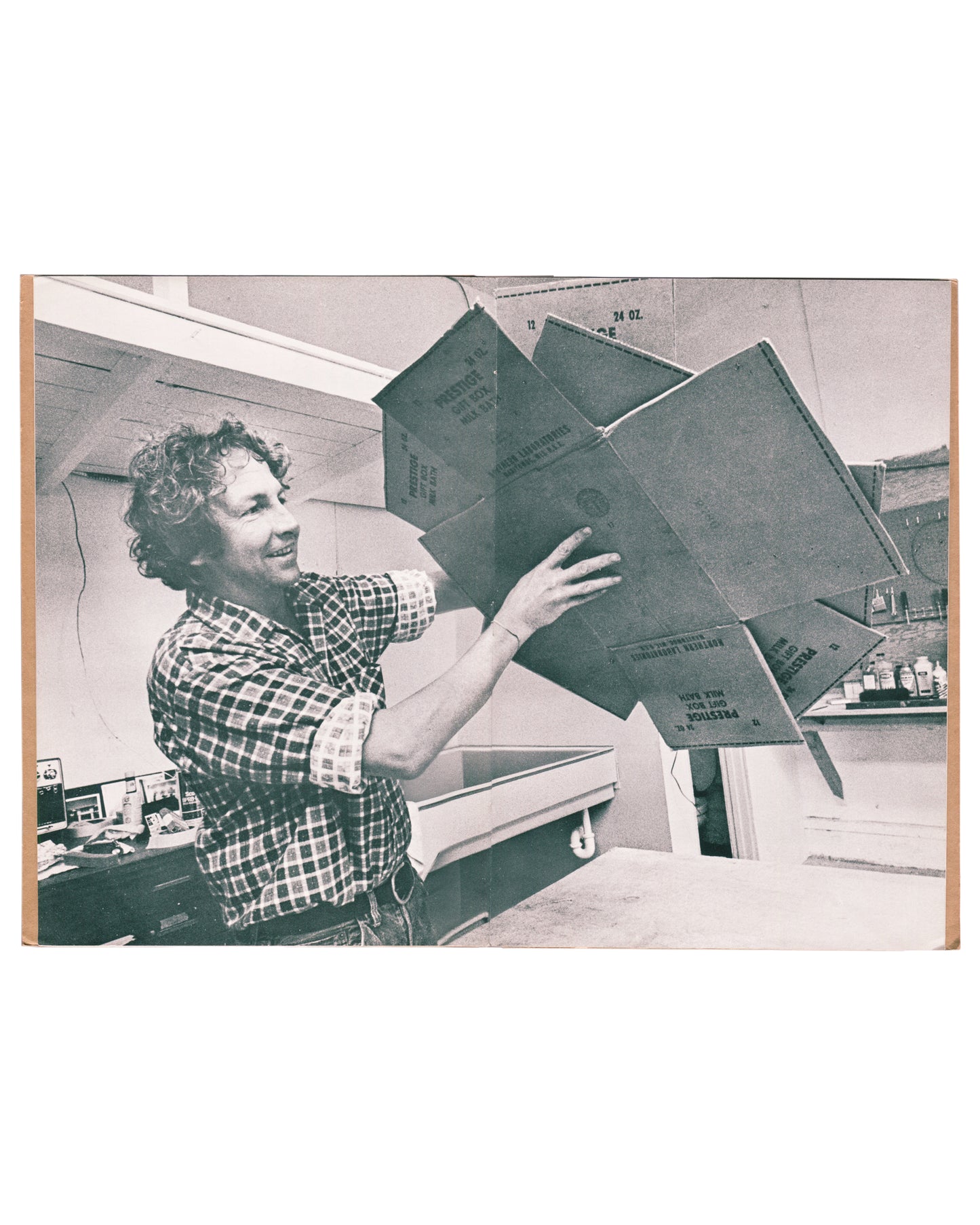 Cardbirds production photograph by Malcolm Lubliner. Rauschenberg holds fanned cardboard panels in Gemini workshop.