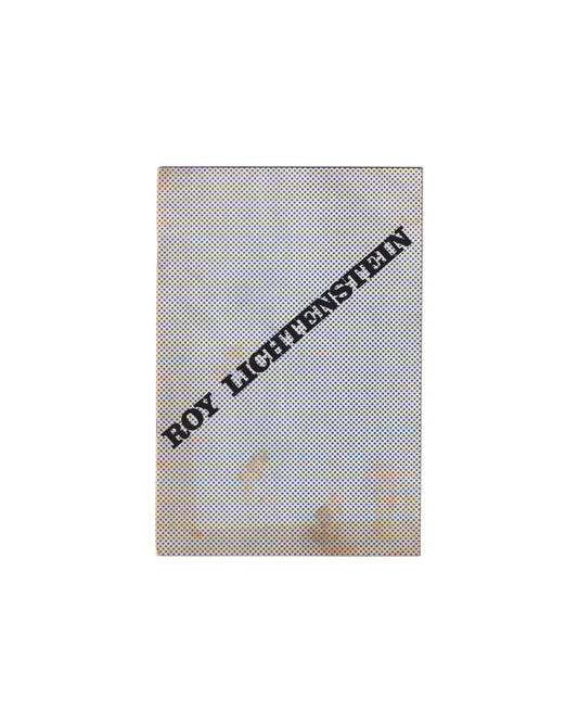 Exhibition catalogue cover, Roy Lichtenstein, Galerie Ileana Sonnabend, Paris, 1965. Full-bleed Benday-dot pattern in blue and black across cream wrappers; artist name ROY LICHTENSTEIN set diagonally in bold black serif capitals from lower-left to upper-right. Age toning and foxing visible at lower corners. Stapled binding.