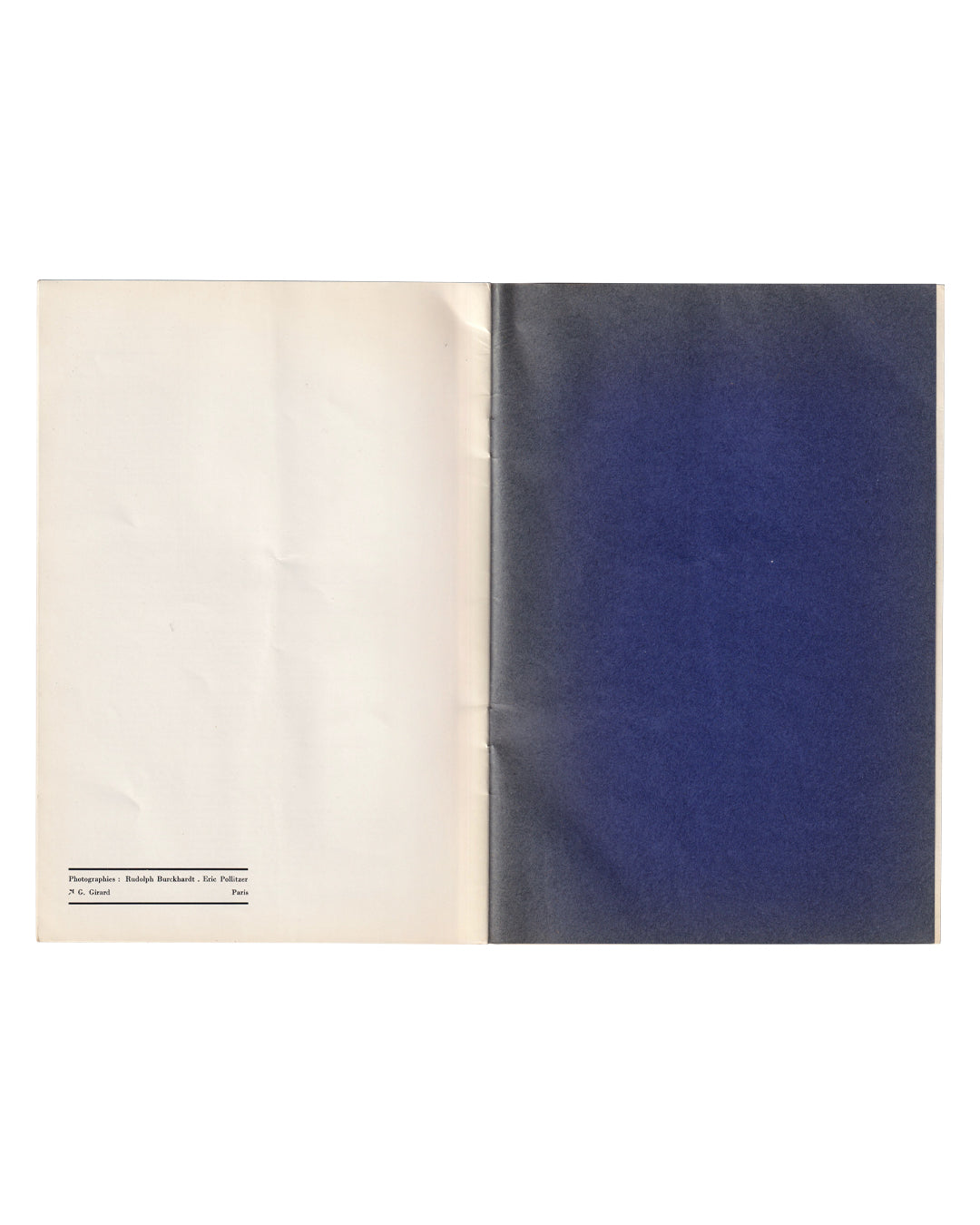 Interior spread, Roy Lichtenstein catalogue, Galerie Ileana Sonnabend, Paris, 1965. Verso: cream page with colophon in small type at lower left reading Photographies: Rudolph Burckhardt, Eric Pollitzer / N.G. Girard, Paris. Recto: inside wrapper printed solid deep blue. Staple binding visible at centre gutter. Catalogue open flat.
