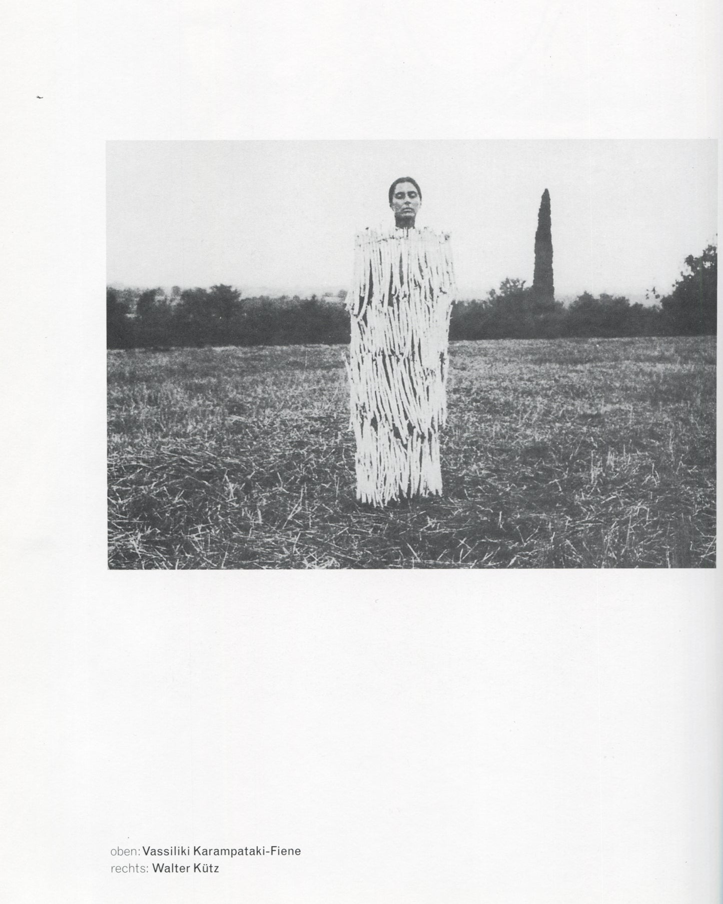 Klaus Rinke, Saldo, Rinke Klasse 1997, Vassiliki Karampataki-Fiene, figure in shredded white costume standing in harvested field, b&w
