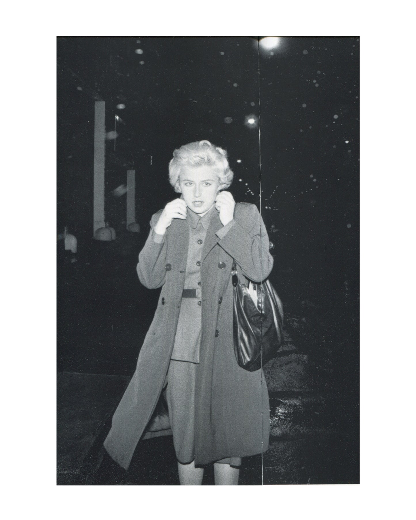 Cindy Sherman, Untitled #54, 1980, b&w Film Still — blonde Sherman in double-breasted coat, clutching collar, handbag, caught outside at night, street lights behind