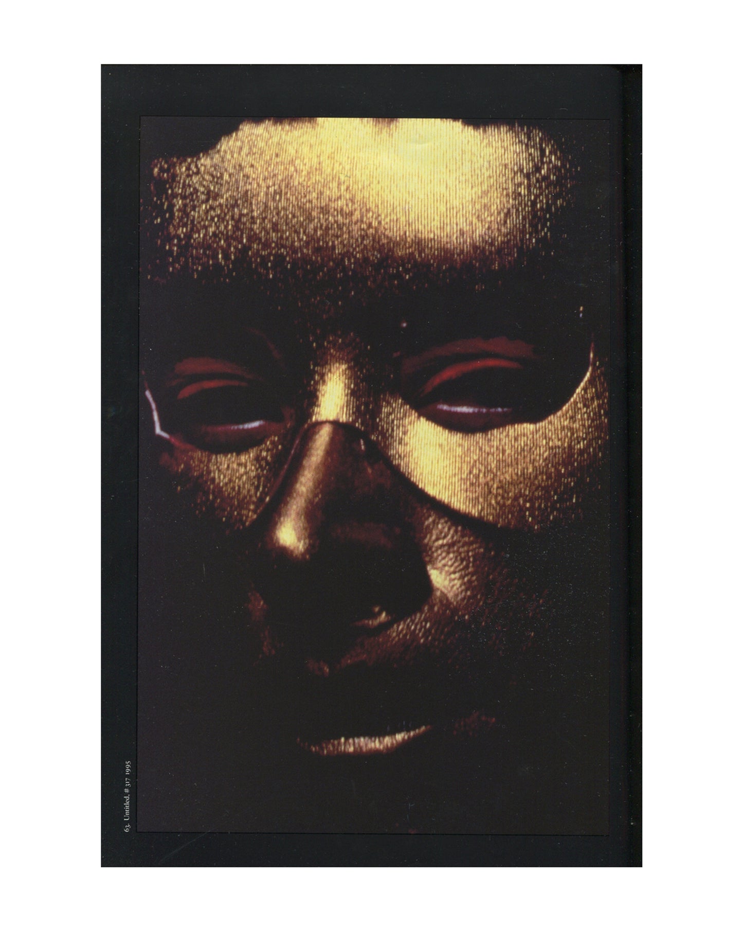 Cindy Sherman, 1997 catalogue, interior: colour Untitled #317, 1995 — gold metallic mask, close-up face, red-rimmed eye slits, black ground; caption lower left
