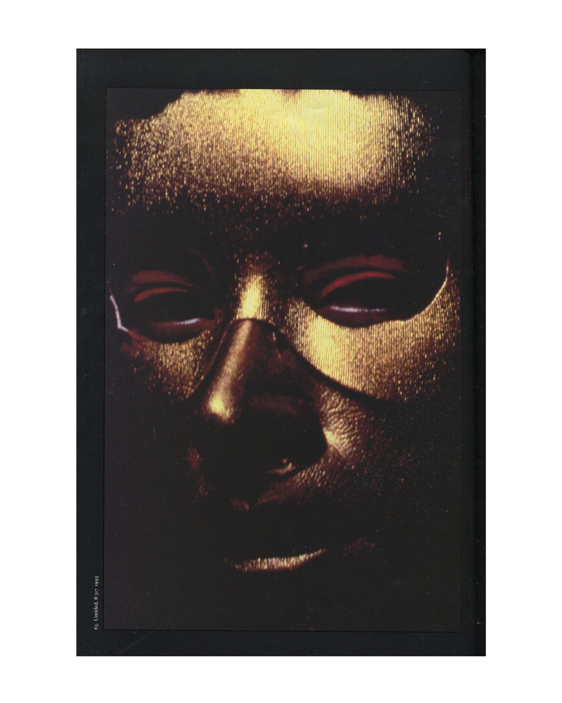 Cindy Sherman, 1997 catalogue, interior: colour Untitled #317, 1995 — gold metallic mask, close-up face, red-rimmed eye slits, black ground; caption lower left
