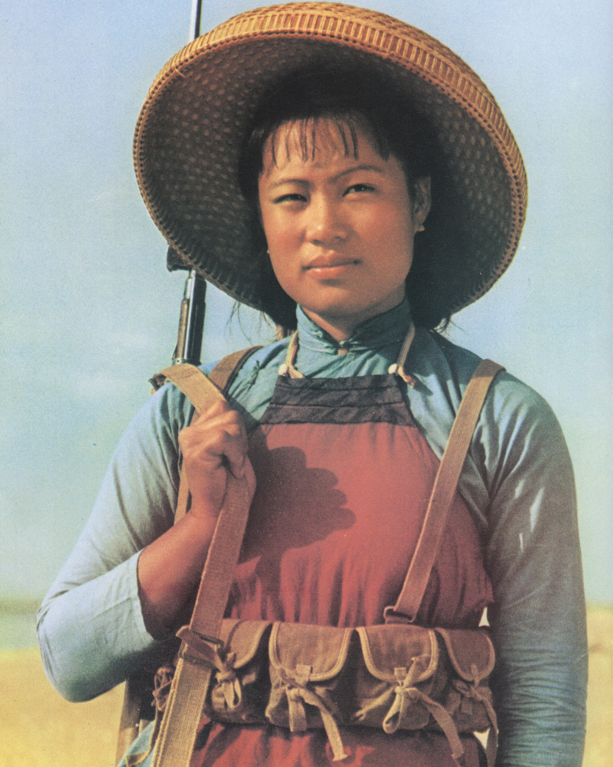 Katharina Sieverding, Grossfotos I–X, 1977, interior spread: colour photograph of female figure in wicker hat and red apron carrying rifle, open landscape