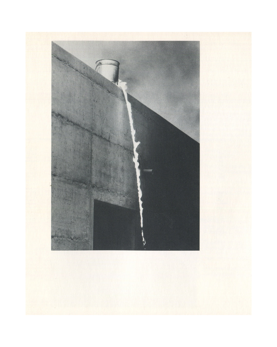 Roman Signer, Fast Changes, interior: b&w photo of metal bucket on concrete wall corner, liquid pouring down facade in thin stream
I