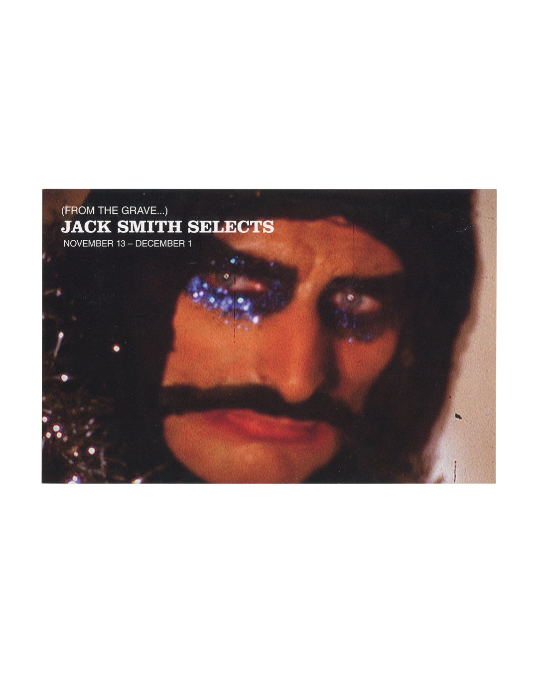 2015 Anthology Film Archives programme card for Jack Smith Selects (From the Grave...), front, colour film still: close-up of a heavily made-up face with blue glitter eye make-up running down the cheek, thick black moustache, dark hair, against a dark background; (FROM THE GRAVE...) / JACK SMITH SELECTS / NOVEMBER 13 – DECEMBER 1 in white type at upper left.