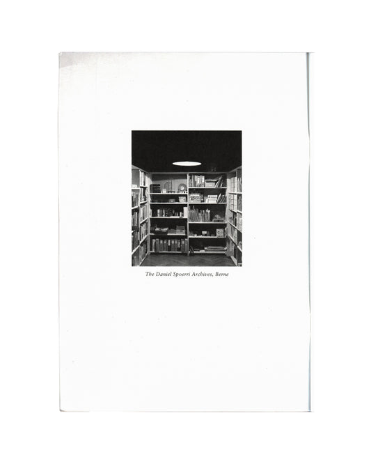 Daniel Spoerri, Profession Obsession 1997, interior: b&w photo of The Daniel Spoerri Archives Berne — shelves of books, binders and objects, oval ceiling light
