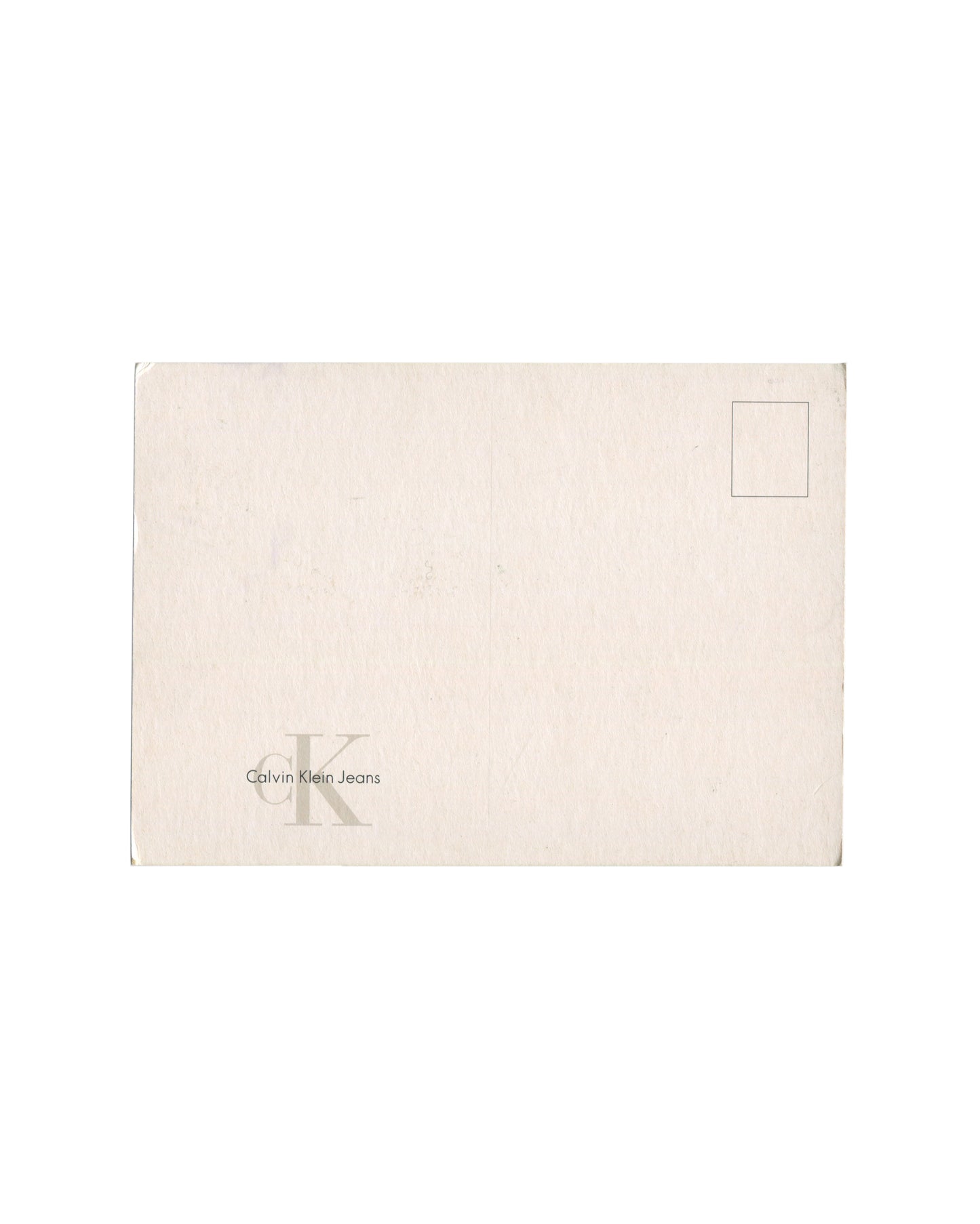Reverse of c. late 1990s–early 2000s Mario Testino Kate Moss Calvin Klein Jeans promotional postcard showing plain cream-white card stock, unused, with standard postcard address lines at right and printed stamp box at upper right; 'cK Calvin Klein Jeans' logo in small grey type at lower left; light surface marks and minor edge wear consistent with storage
