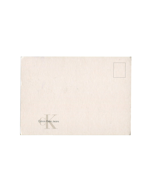 Reverse of c. late 1990s–early 2000s Mario Testino Kate Moss Calvin Klein Jeans promotional postcard showing plain cream-white card stock, unused, with standard postcard address lines at right and printed stamp box at upper right; 'cK Calvin Klein Jeans' logo in small grey type at lower left; light surface marks and minor edge wear consistent with storage