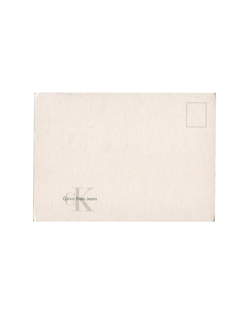 Reverse of c. late 1990s–early 2000s Mario Testino Kate Moss Calvin Klein Jeans promotional postcard showing plain cream-white card stock, unused, with standard postcard address lines at right and printed stamp box at upper right; 'cK Calvin Klein Jeans' logo in small grey type at lower left; light surface marks and minor edge wear consistent with storage