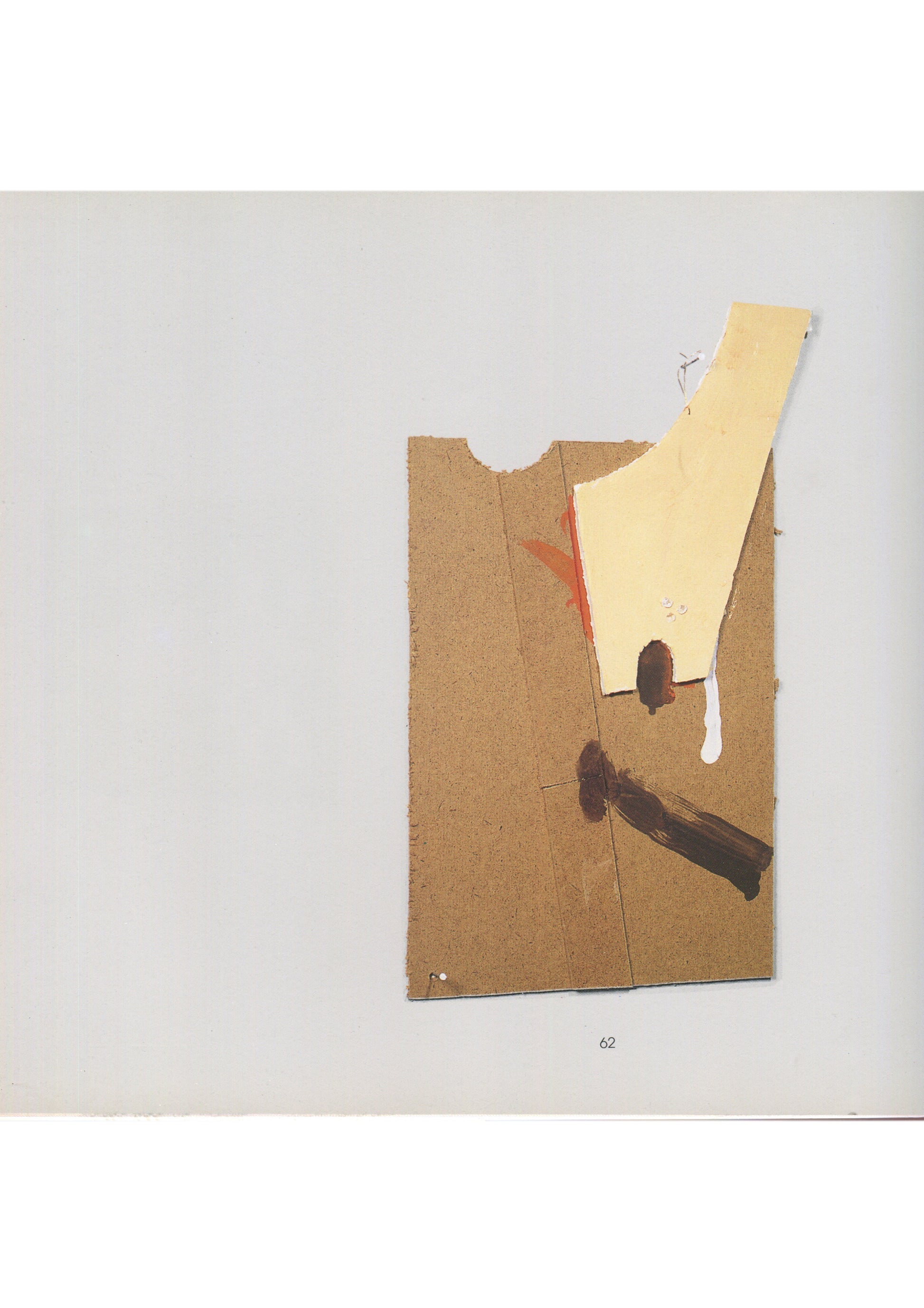nterior page 62 from Richard Tuttle, Warm Brown 1–67 and Mesa Pieces, Kärntner Landesgalerie, c. 1990s, showing a colour reproduction of an untitled work comprising two overlapping pieces of torn and cut cardboard — a larger tan corrugated sheet and a smaller pale yellow piece — pinned to a white wall, with a small red mark and a drip of white paint visible on the surface.