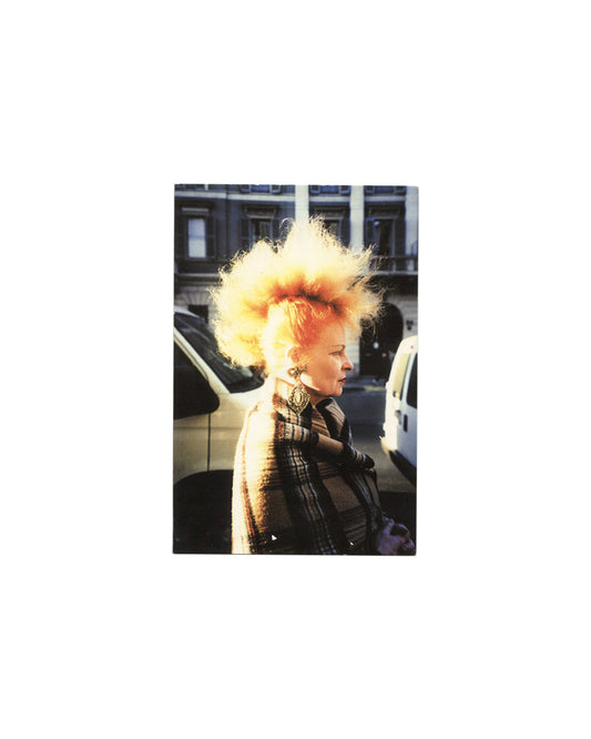 Postcard recto, Tim Hailand, Recent Works, Coloredge, New York, 2002. Colour photograph by Tim Hailand — Vivienne Westwood, Milan, January 2002. Profile view; woman in dark plaid coat and large ornate earring; voluminous backlit orange-blonde hair against urban street background; parked vehicles and Georgian-style building behind. Good vintage condition, light surface marking.