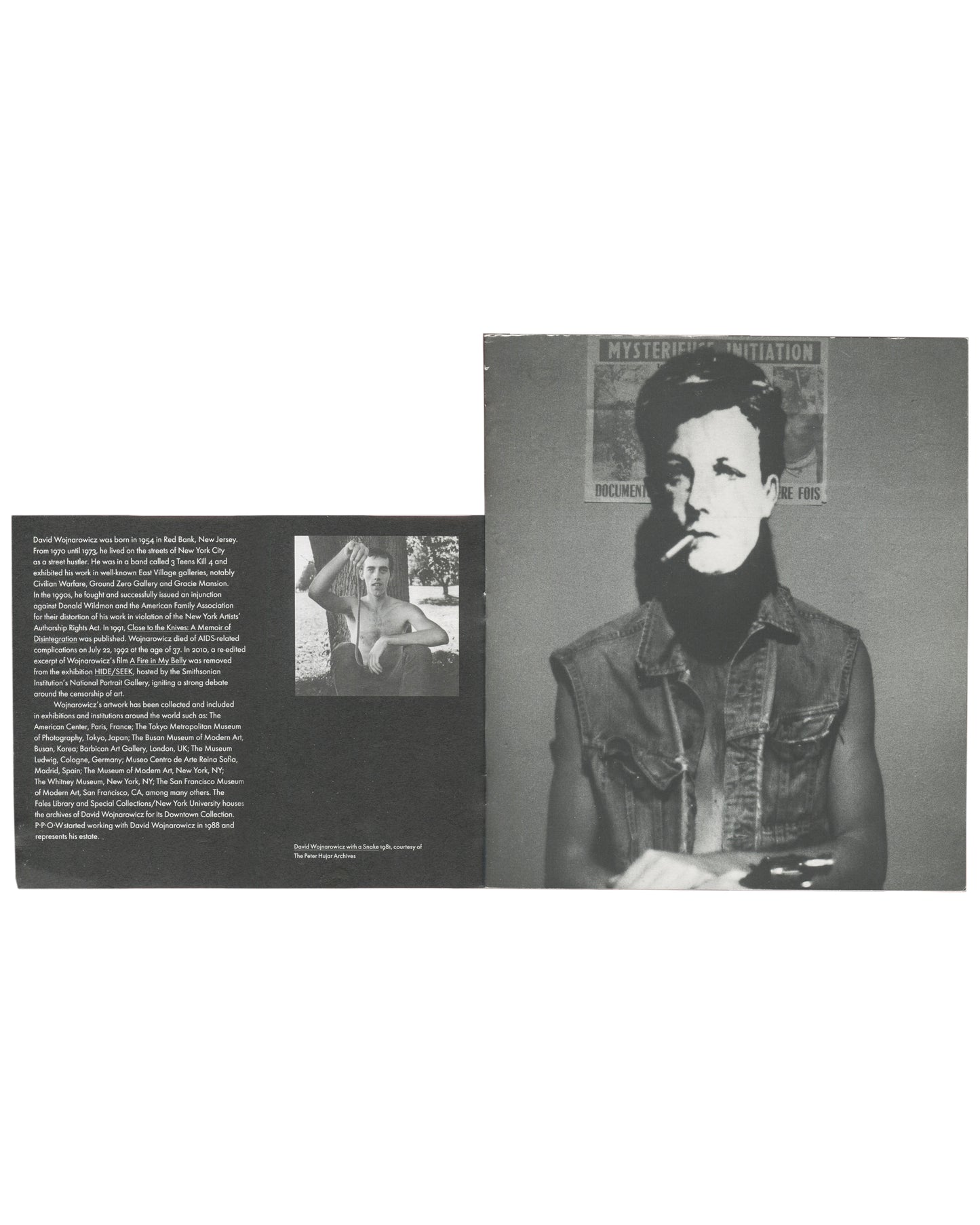 Interior spread, The Rimbaud Series / Survival AIDS, 2012. Left page: biography text in small sans-serif type — David Wojnarowicz biographical essay; small black-and-white photograph inset, shirtless figure. Right page: full-bleed black-and-white photograph — masked figure (Arthur Rimbaud mask) smoking a cigarette, wearing a denim jacket, against a wall with partially visible poster 'MYSTERIOUS INITIATION / DOCUMENT… RE FOIS'. Caption lower right: 'David Wojnarowicz with a Snake 1981, courtesy of The Peter 