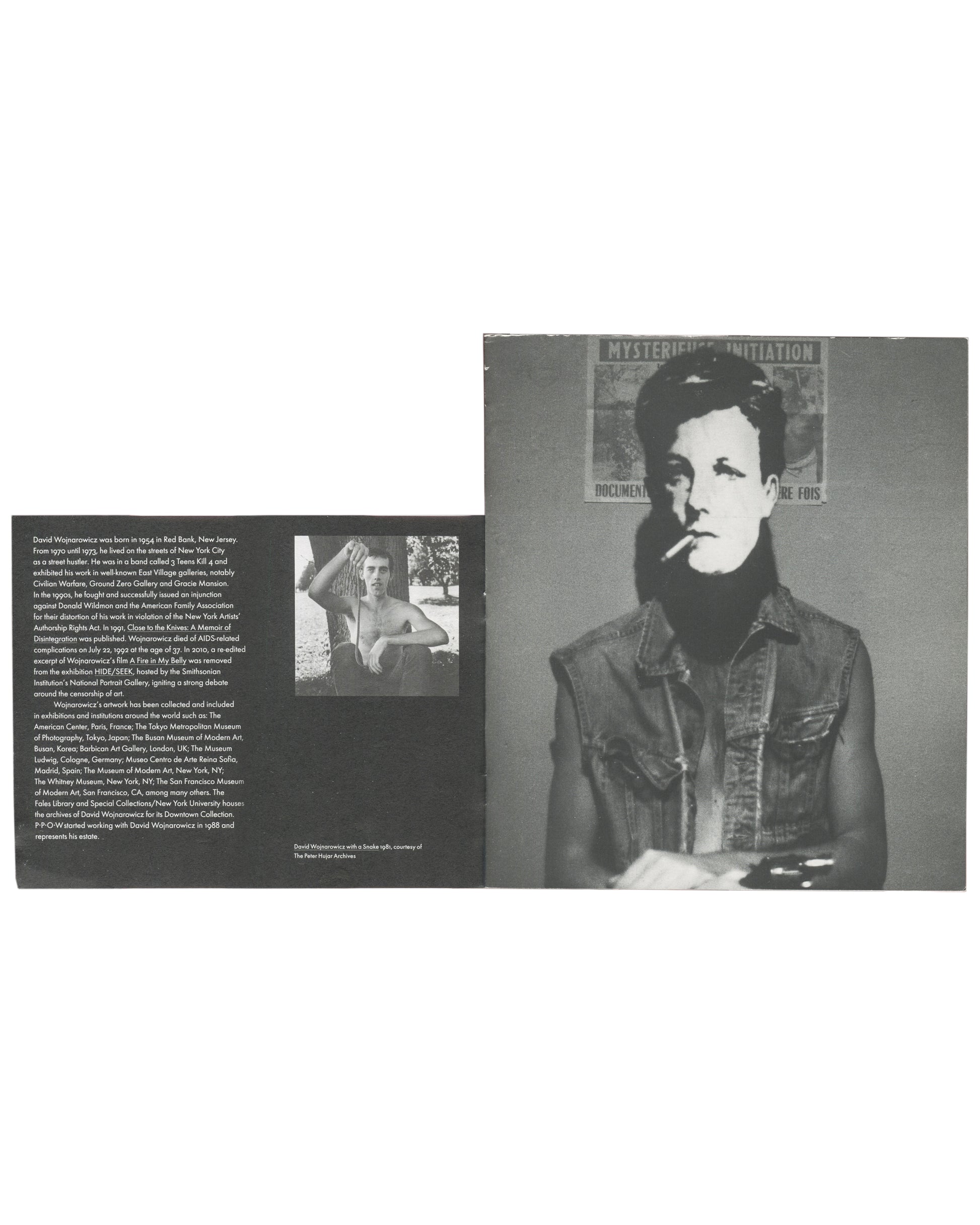 Interior spread, The Rimbaud Series / Survival AIDS, 2012. Left page: biography text in small sans-serif type — David Wojnarowicz biographical essay; small black-and-white photograph inset, shirtless figure. Right page: full-bleed black-and-white photograph — masked figure (Arthur Rimbaud mask) smoking a cigarette, wearing a denim jacket, against a wall with partially visible poster 'MYSTERIOUS INITIATION / DOCUMENT… RE FOIS'. Caption lower right: 'David Wojnarowicz with a Snake 1981, courtesy of The Peter 