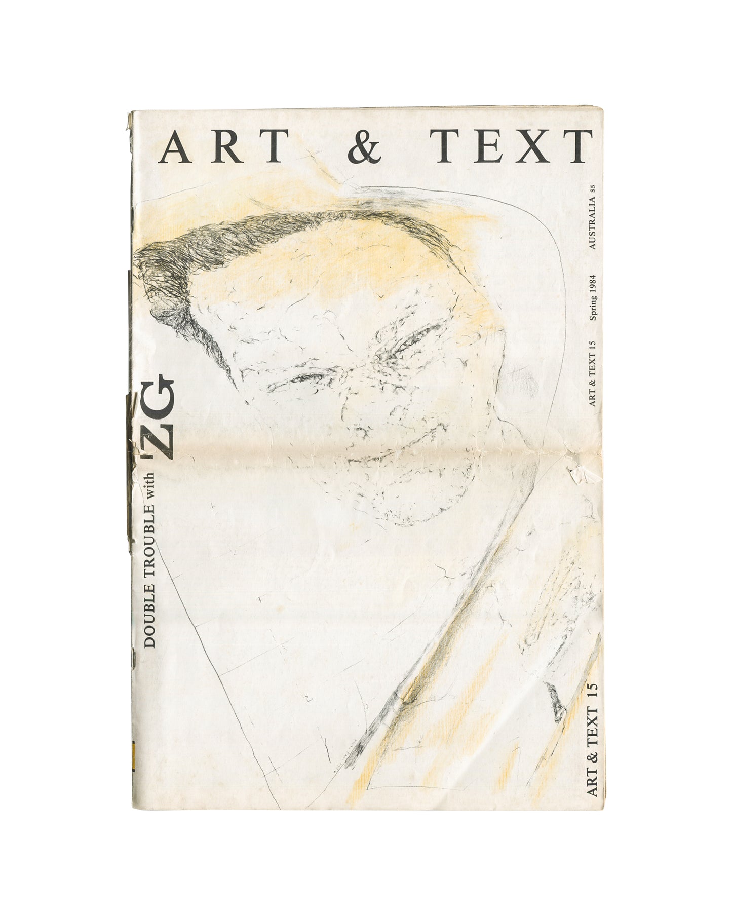 Magazine cover, ZG No. 11 / Art & Text 15: Double Trouble, ZG Magazine / Art & Text, New York / Melbourne, 1984. Edited by Rosetta Brooks. Large-format staple-bound periodical, 28 × 42 cm. Yellow horizontal band upper third — bold black 'ZG' logotype left; white sans-serif 'DOUBLE TROUBLE' right; below band: 'with ART&TEXT'. Full-bleed black-and-white photograph — two female figures in hazy backlit environment; foreground figure in short slip dress, short dark hair; background figure in dark structured outf