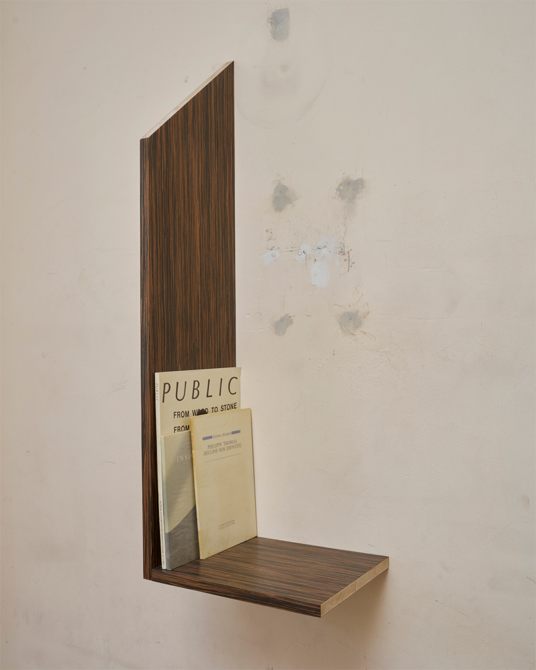  James Mullord, Bookshelf, Publications, displaying publications including PUBLIC against a marked gallery wall.
